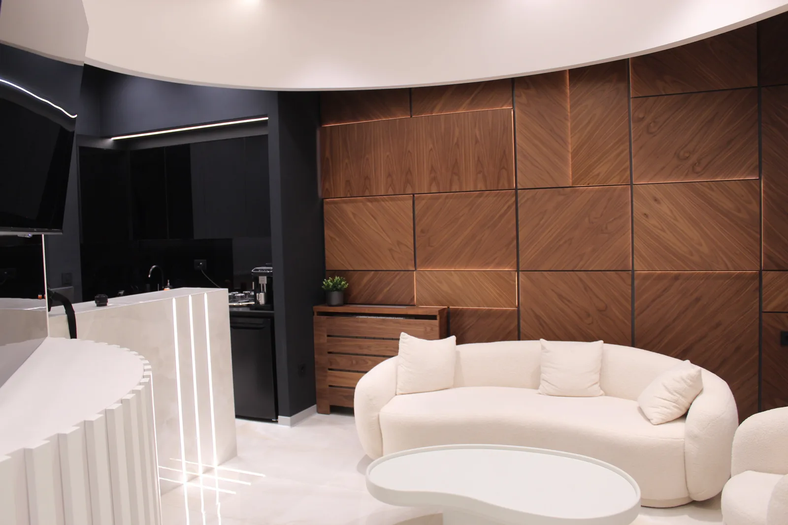 The clinic lounge: a curved sofa against a walnut-panelled wall, with the coffee bar behind.